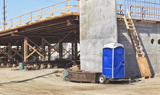 a row of blue portable restrooms set up on a construction site